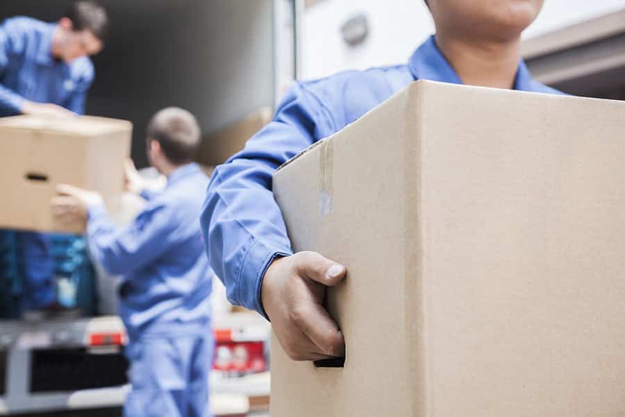 medical personnel with gloves carrying a brown box while other medical personnel unload boxes