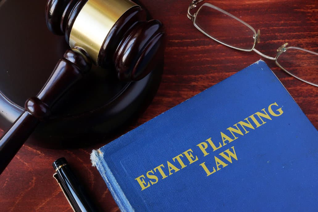 a book titled estate planning law and a gavel with glasses and a pen