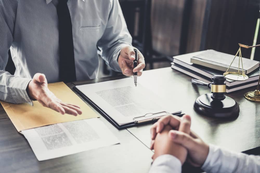 two men sitting at a table with documents conversing