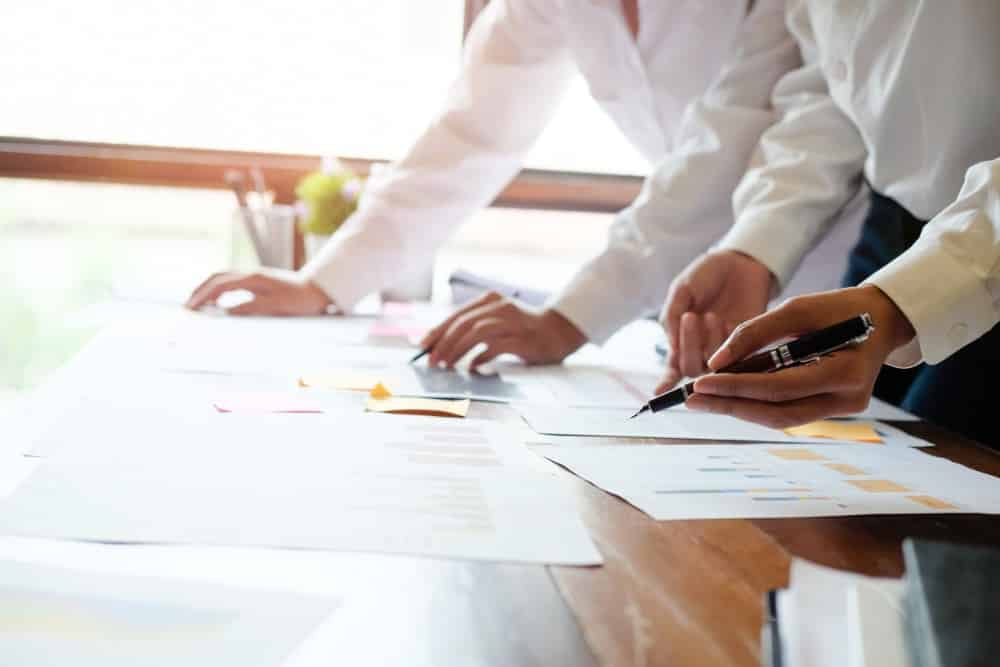 two people looking over paperwork on a wood table