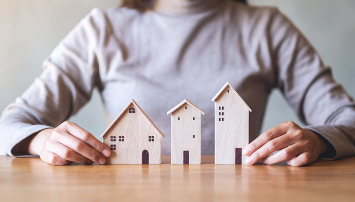 Closeup image of a woman holding wooden house models on the table
