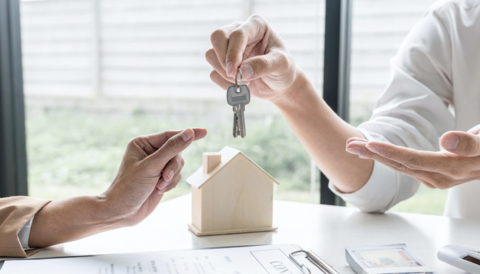 Estate agent giving house keys to client after signing rental lease contract of sale purchase agreement concerning mortgage loan offer for and house insurance