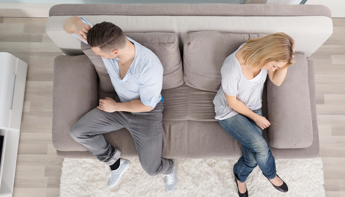 frustrated couple sitting far apart on couch