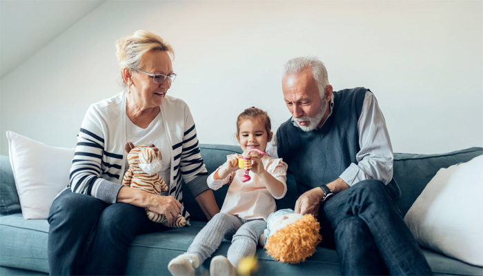 grandparents sitting on couch with granddaughter