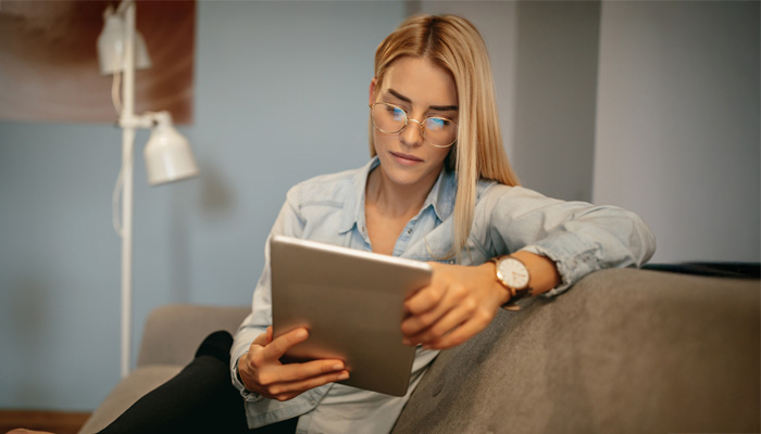 woman sitting on couch reading her tablet
