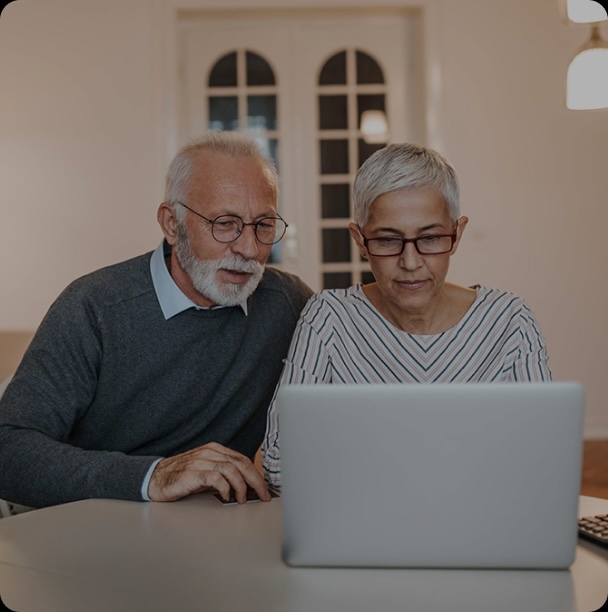 two elderly people using a laptop