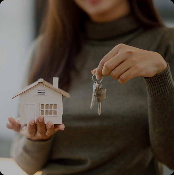 woman holding a model of a house and keys